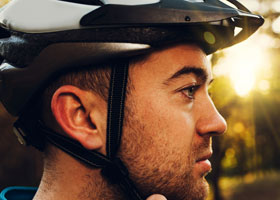A man wearing a bicycle helmet. Wearing bicycle helmets has been found to reduce head injury by 48%.