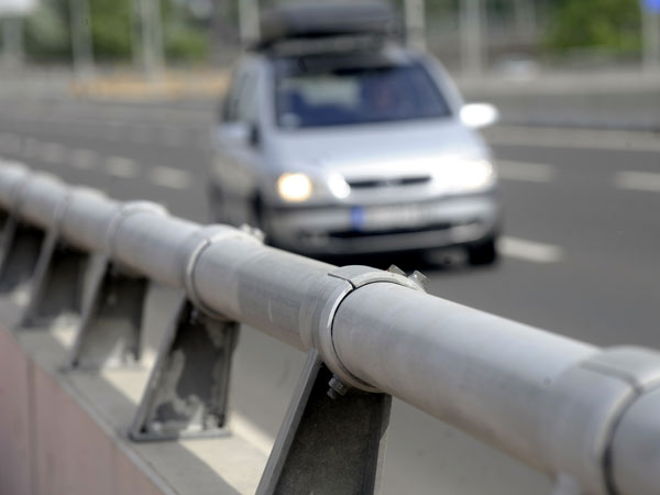 A car driving on a road with a safety fence.